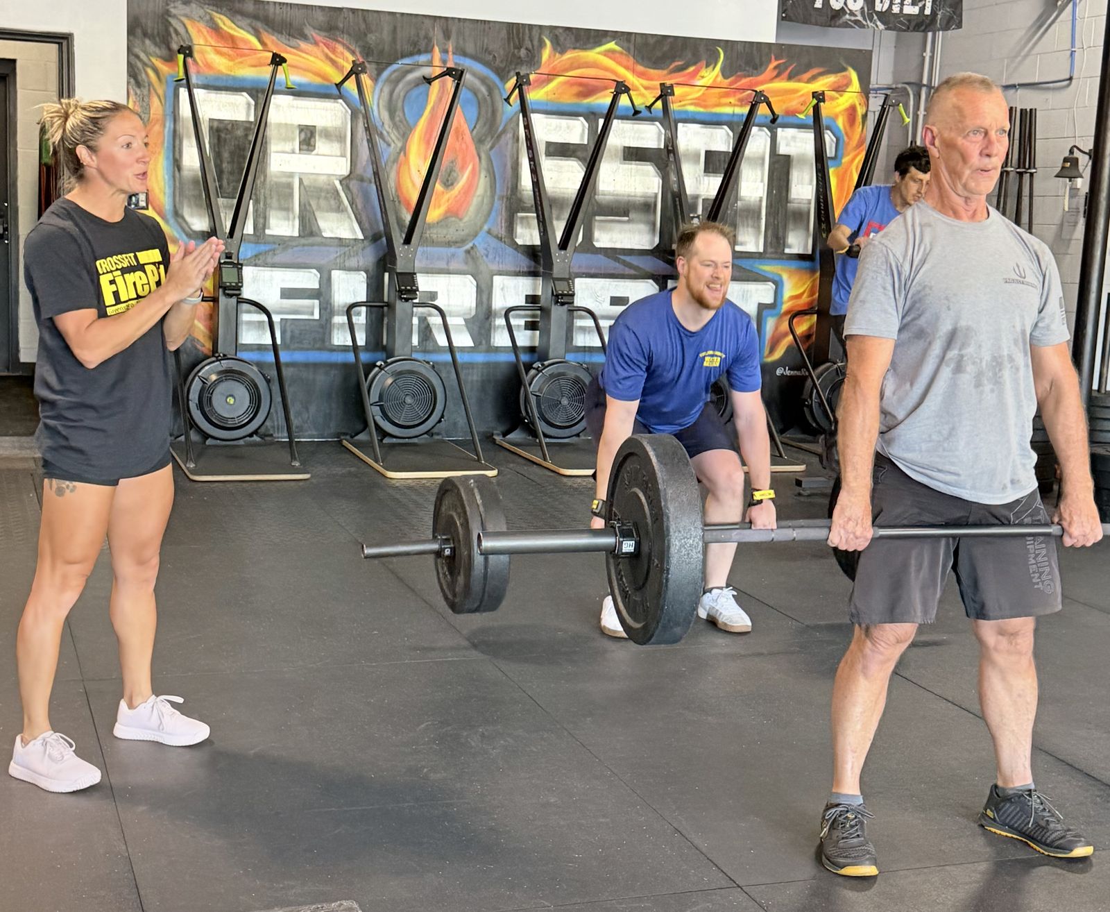 A masters athlete lifting on the floor at CrossFit FirePit with a coach cheering